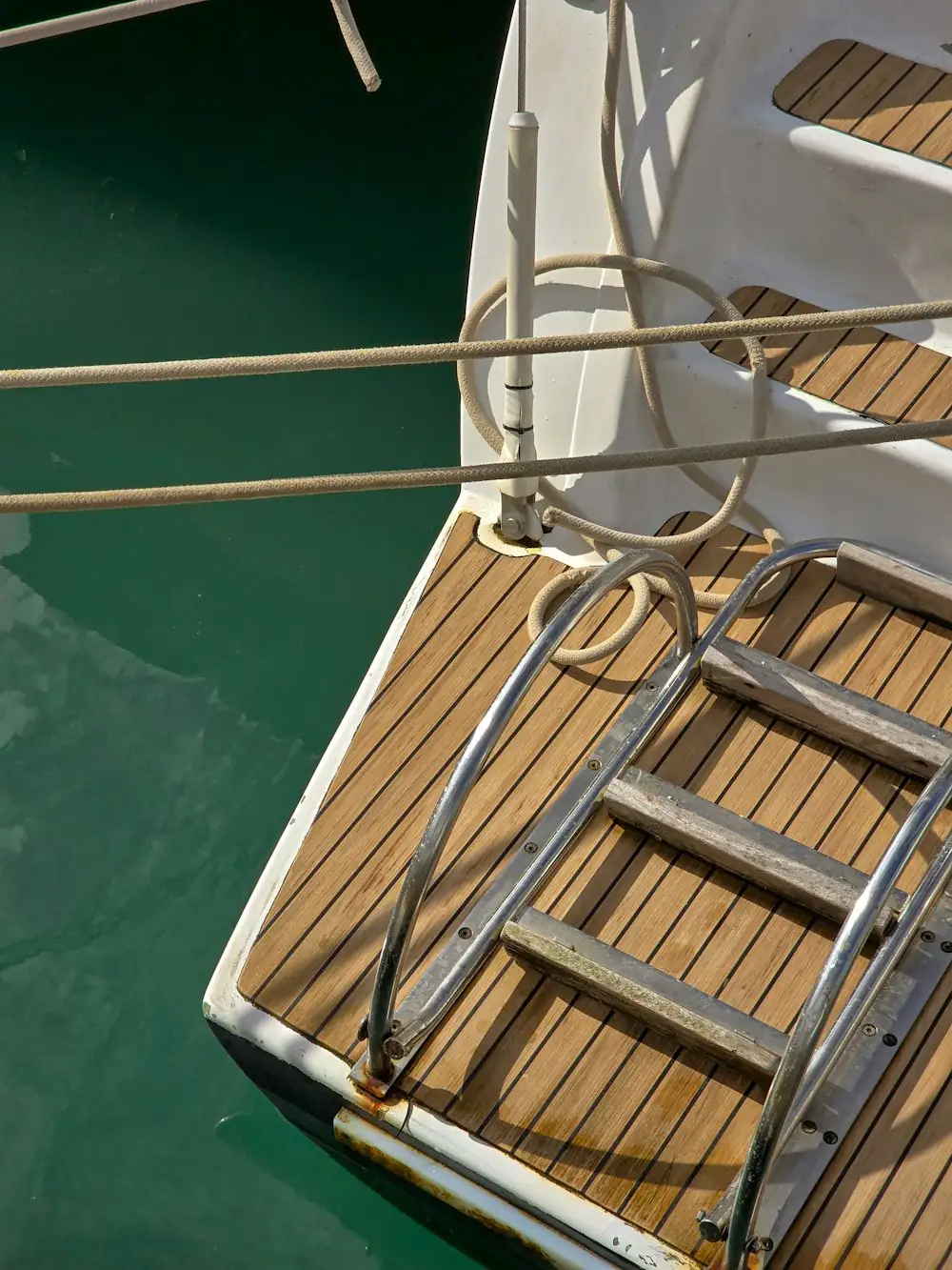 Teak stern deck and boarding ladder of a moored sailing yacht