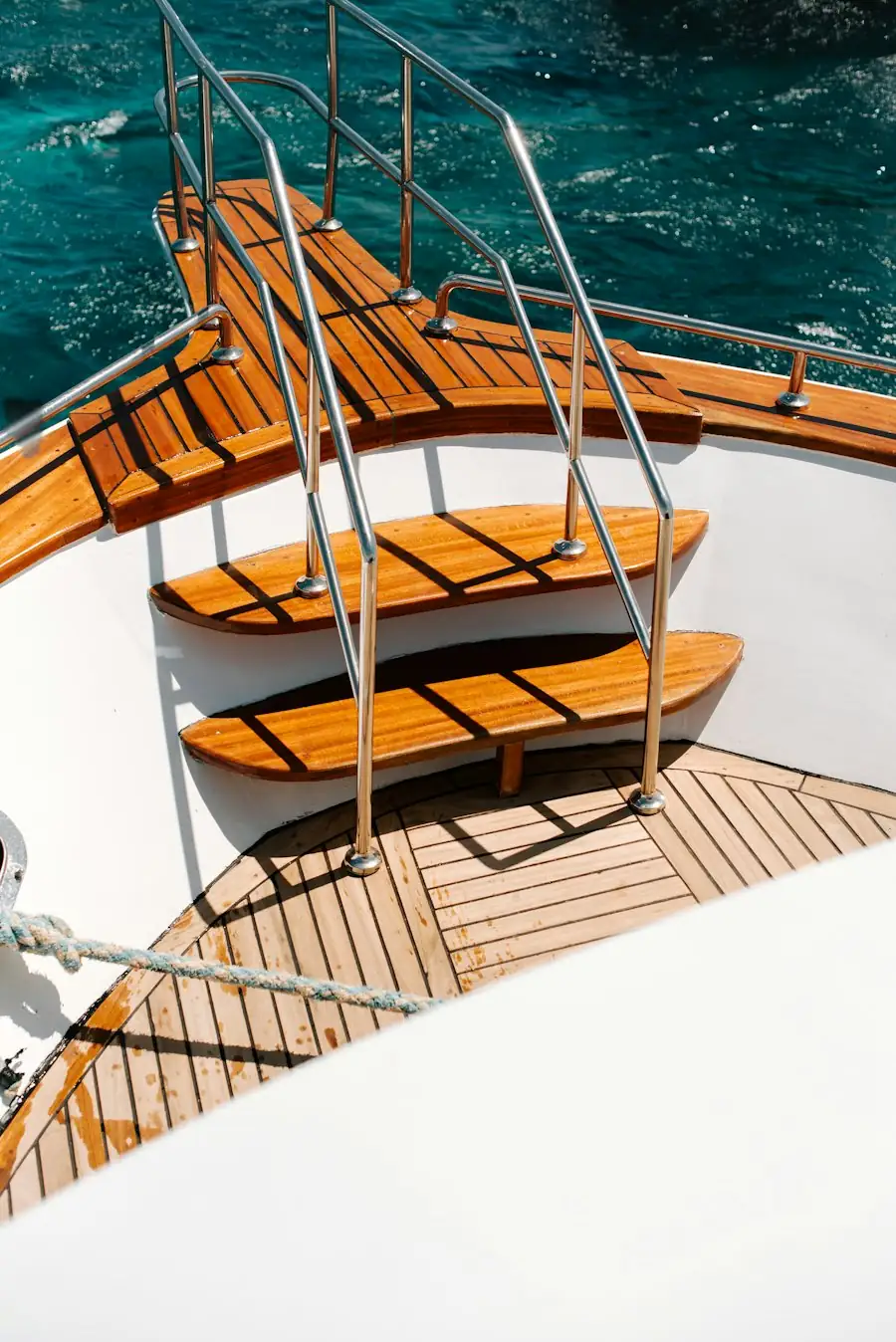 Teak deck steps with stainless steel handrails on a yacht