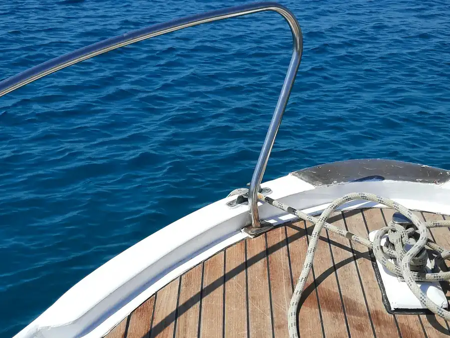 Clean teak foredeck and stainless bow rail on a white boat